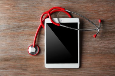 Kırmızı stetoskop ve tablet ahşap arka plan üzerinde