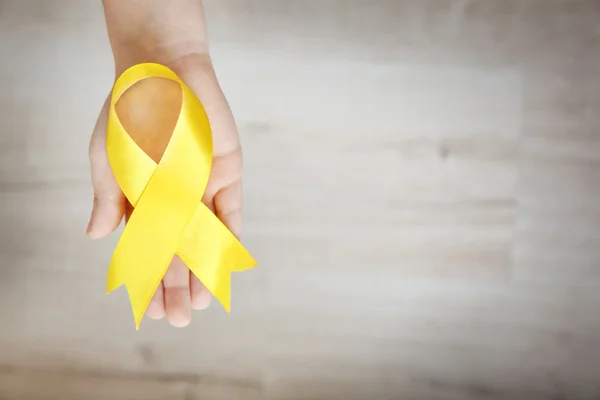 Baby hand holding yellow ribbon — Stock Photo, Image