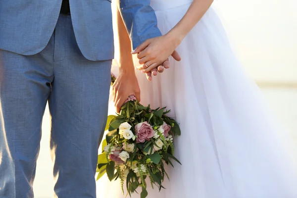 Noiva e noivo mãos no pôr do sol fundo — Fotografia de Stock