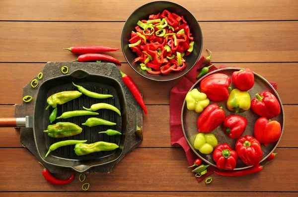 Fresh peppers on plates and pan — Stock Photo, Image