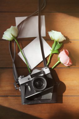 Vintage fotoğraf makinesi, fotoğraf ve güzel gül ahşap masa üzerinde
