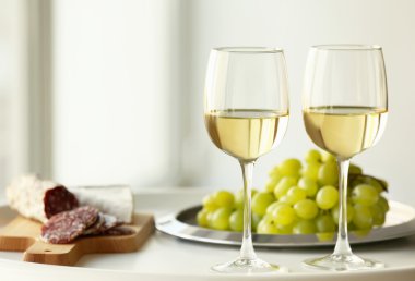 Glasses with white wine and grape on a table clipart