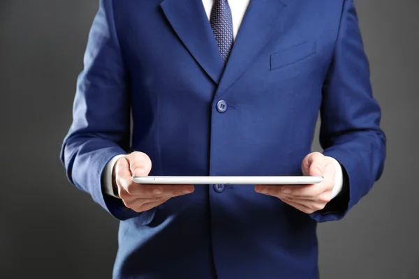 Empresário com tablet sobre fundo cinza — Fotografia de Stock
