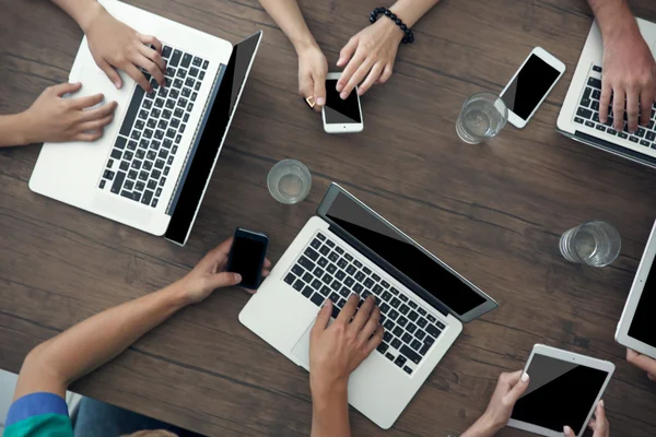 Personnes avec des gadgets à la table en bois — Photo