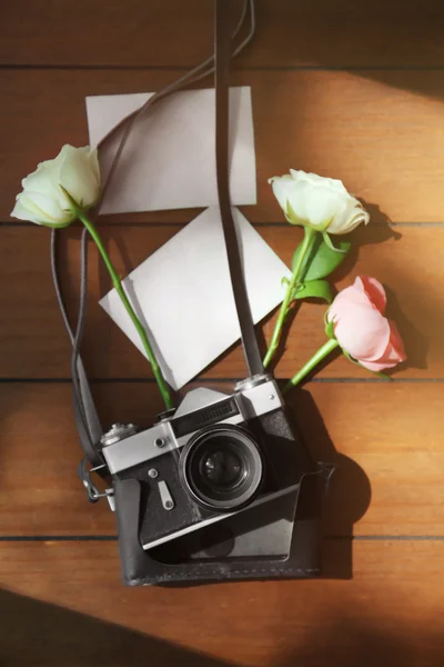 Vintage camera, foto's en mooie rozen op de houten tafel — Stockfoto