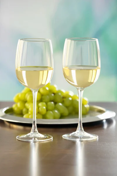 Очки с белым вином и виноградом на столе — стоковое фото