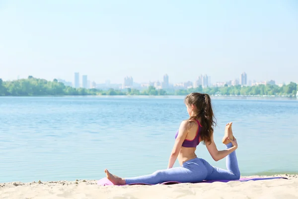 Vrouw doet yoga door rivier — Stockfoto