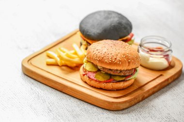 Ahşap kesme tahtası üzerinde iki farklı burger
