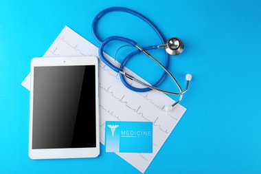 Steteskop ve tablet üzerinde mavi arka plan
