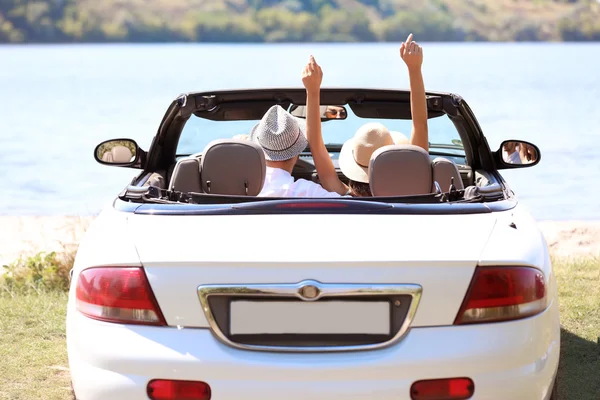 Couple in car on river shore