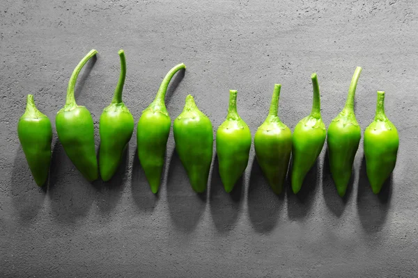 Zelené papriky na šedý stůl — Stock fotografie