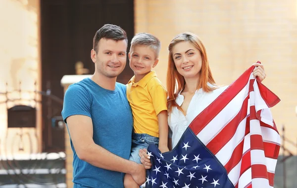 Família feliz com bandeira americana ao lado de sua casa — Fotografia de Stock