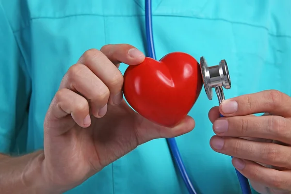 Homme médecin tenant coeur rouge et stéthoscope, gros plan — Photo