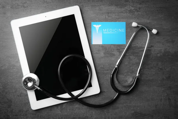 Orvosi koncepció. Tablet és sztetoszkóp, a névjegykártyát a szürke háttér — Stock Fotó