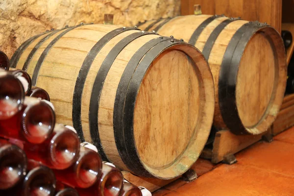 Holzfässer und Flaschen mit Wein im Keller — Stockfoto