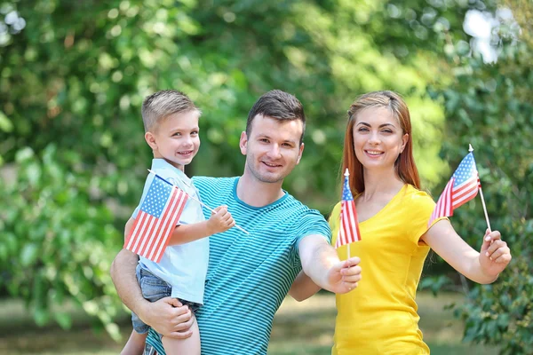 Familia feliz con banderas americanas en el parque Fotos de stock libres de derechos