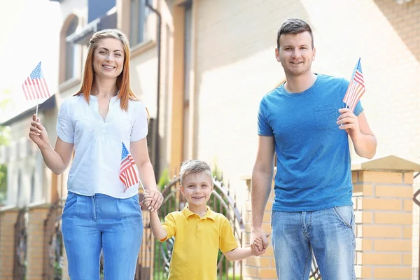 Familia feliz con banderitas americanas en el patio Imágenes de stock libres de derechos