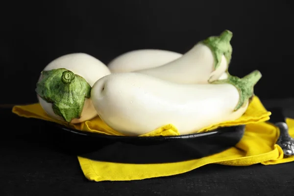 White aubergines with yellow napkin on plate on black background — Stock Photo, Image