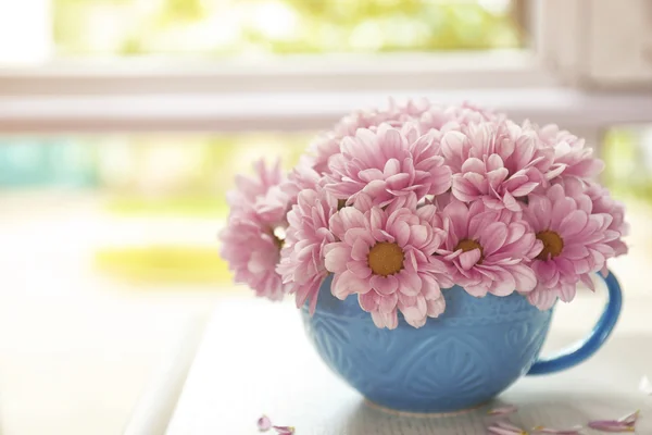 Strauß schöner Blumen in einer Tasse auf einem Tisch — Stockfoto