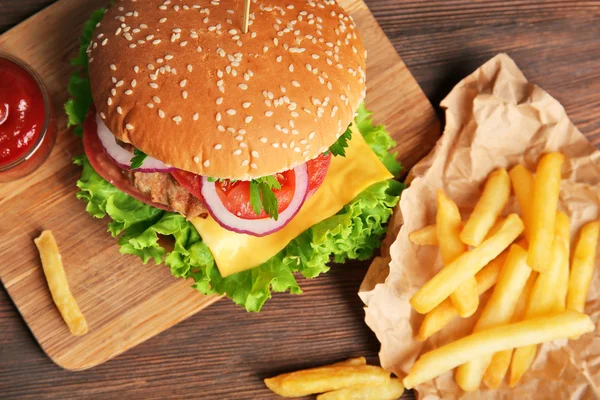 Chutné cheeseburger s hranolky na dřevěný stůl — Stock fotografie