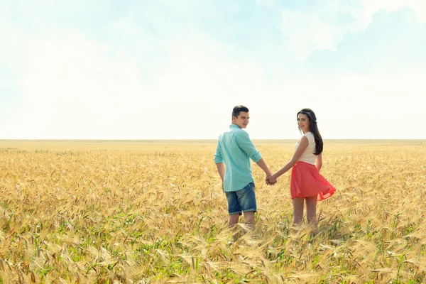 Молодая пара держится за руки на прекрасном поле — стоковое фото