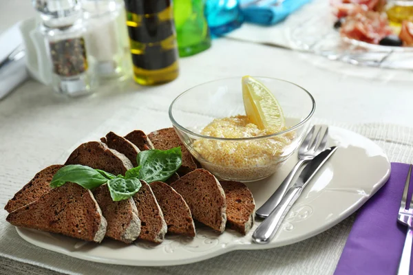 Piatto con pane e caviale sul tavolo di legno nel caffè — Foto Stock