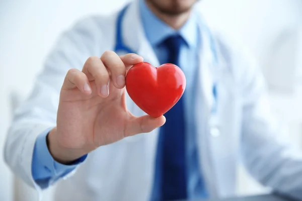 Male doctor holding red heart in clinic office, closeup — Stock Photo, Image