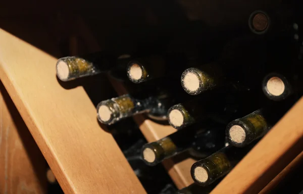 Botellas con vino en estantes de madera en bodega — Foto de Stock