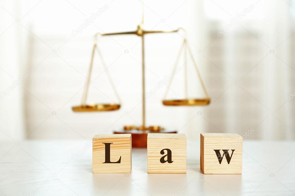 Wooden cubes with word LAW and scales on a table