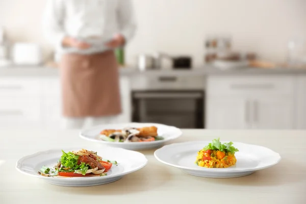 Platen met smakelijke gerechten op de keukentafel, close-up — Stockfoto