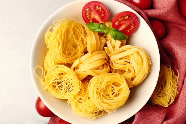 Bowl with pasta nests and cherry tomatoes on table, close up — Stock Photo, Image