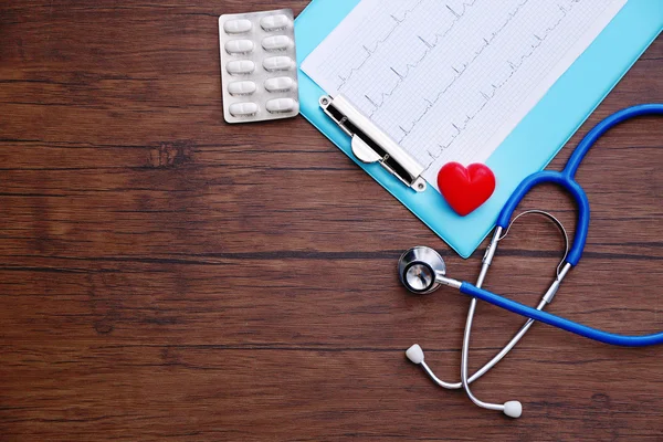 Stethoskop, Pillen und rotes Herz mit Papier-Elektrokardiogramm — Stockfoto