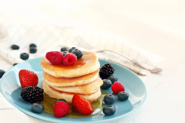 Leckere Pfannkuchen mit Beeren und Honig auf blauem Teller — Stockfoto