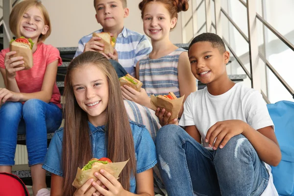 小学生の学校の階段に座ってサンドイッチを食べる — ストック写真