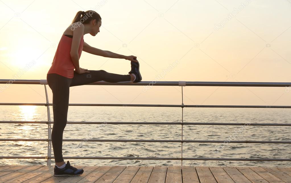 Young woman doing exercises on pier