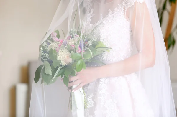 Belle mariée tenant bouquet sous voile — Photo