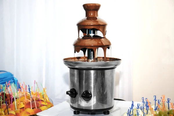 Chocolate fondue fountain and fruit on a table — Stock fotografie