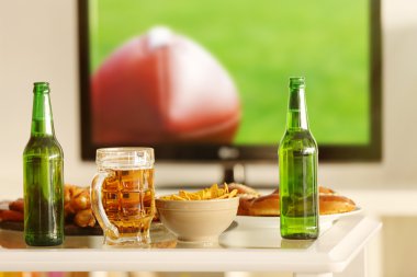 Lezzetli aperatifler ve şişe bira mutfak masasında Tv arka plan bulanık karşı ile