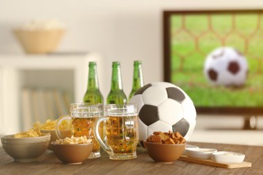 Lezzetli aperatifler ve şişe bira mutfak masasında Tv arka plan bulanık karşı ile