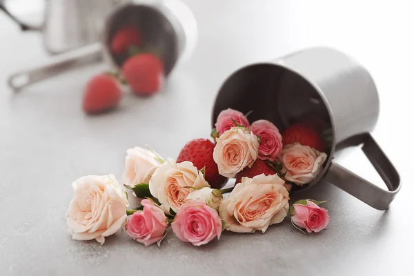 Roses and strawberries with cup on table