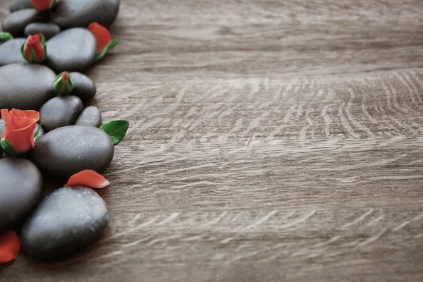 Wellness-Steine mit Rose und Blütenblättern auf Holzgrund — Stockfoto