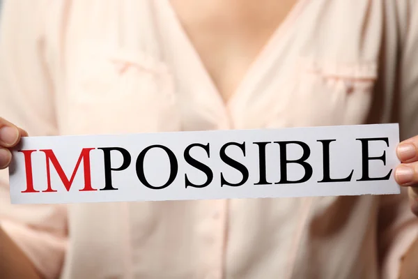 Woman holding word IMPOSSIBLE, close up — Stock Photo, Image