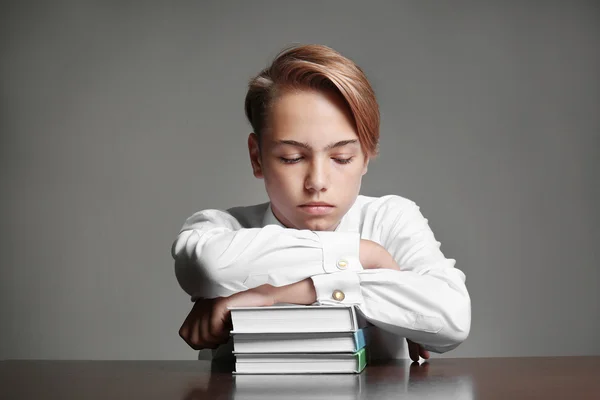 灰色の背景の本の上に横たわる疲れた少年 — ストック写真