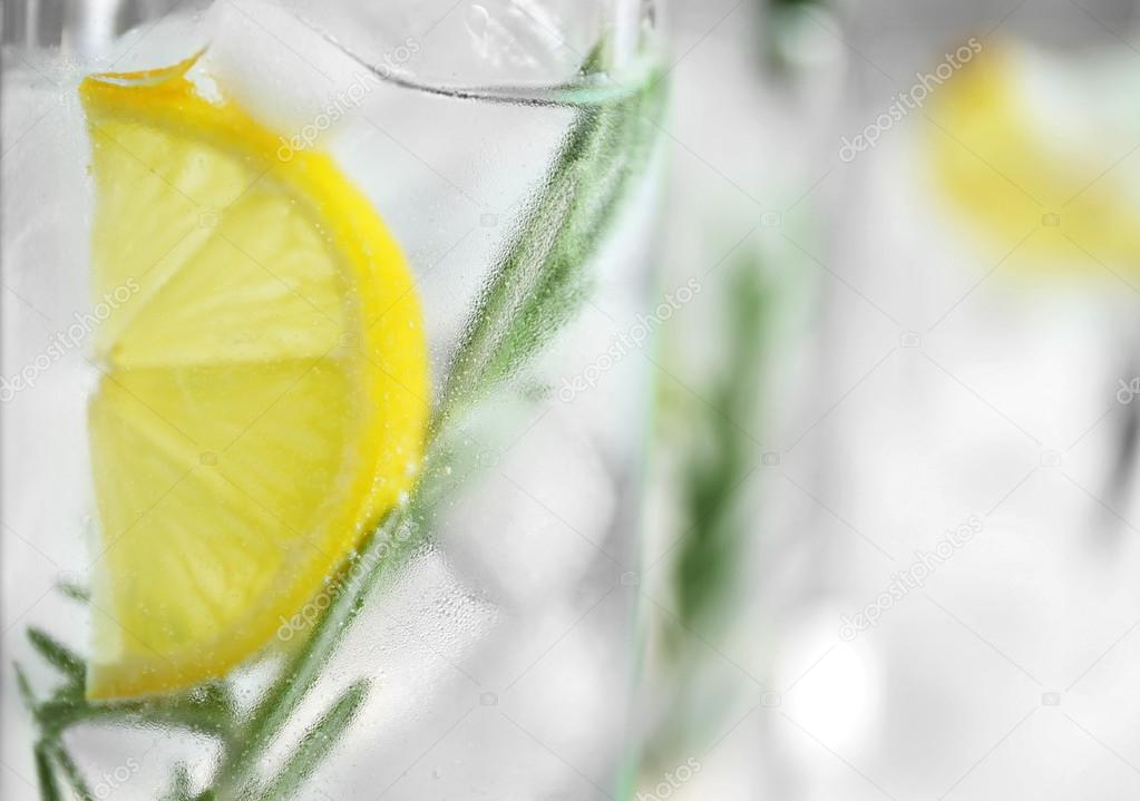 Glass of cocktail with ice, lemon and rosemary closeup