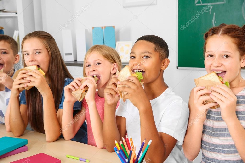 Schoolchildren having lunch in classroom
