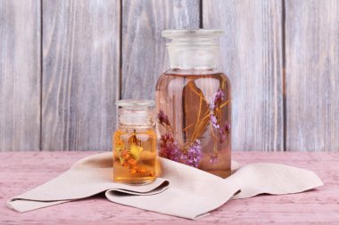 ahşap duvar önünde ahşap bir masa üzerinde bitki tentür şişe