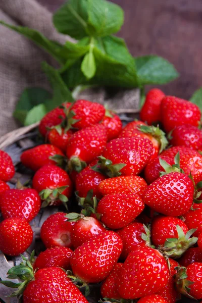 Maturare dolci fragole su stuoia di vimini, su sfondo di legno a colori — Foto Stock