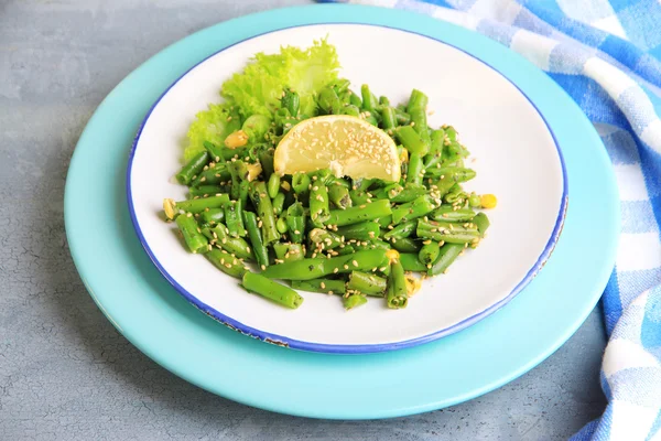 Salad with green beans and corn, sesame seeds on plate, on color wooden background — Stock Photo, Image