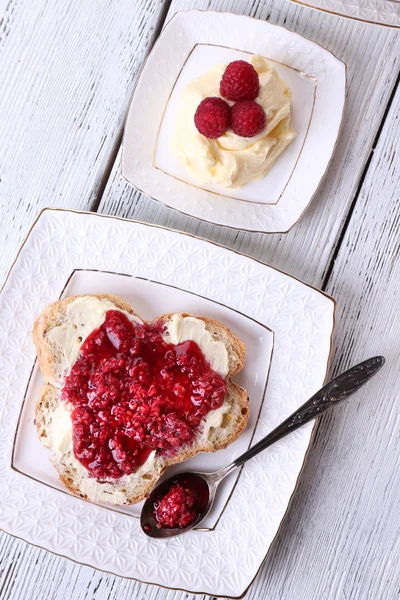 Tostadas frescas con mantequilla casera y mermelada de frambuesa en plato sobre fondo de madera — Foto de Stock