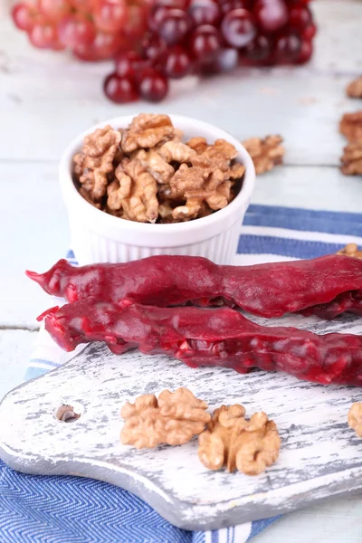 Sabrosos dulces orientales (churchkhela) y nueces frescas, sobre fondo de madera —  Fotos de Stock